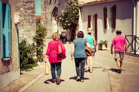 back view of a group of tourists walking in a village in summerの写真素材