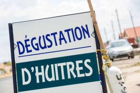 Closeup view of sign - "Oyster Tasting" ("DÃ©gustation d'Huitres" in French) in an harbourの写真素材