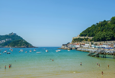 San Sebastian, Spain - August 09, 2012: Bay of San Sebastian with bathers in the foreground, pleasure boats and a mountain in the background and some buildings on the right sideのeditorial素材