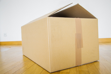 Single cardboard box on wooden floor for shifting house from one place to another during demotion