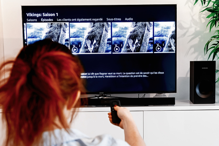 Benon, France - December 30, 2018: Woman holding a tv remote control In the process of selecting the viking success series proposed by Prime Video, a video-on-demand service created by Amazon.comのeditorial素材