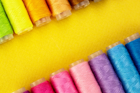 Colorful yellow thread spools over bright yellow background, above view, with copy spaceの写真素材