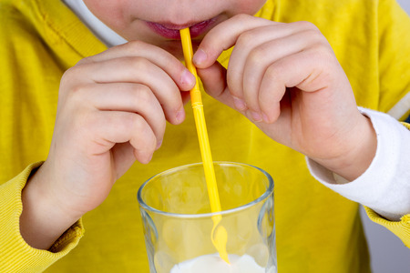 Cute boy drinks milk using a drinking strawの写真素材