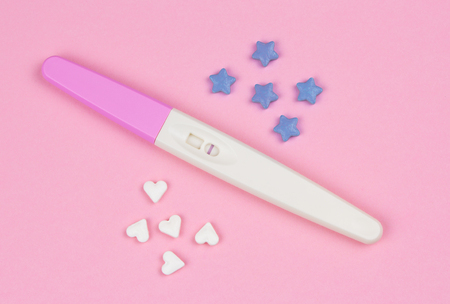 positive result on the pregnancy test with little hearts and blue stars over a pink backgroundの写真素材