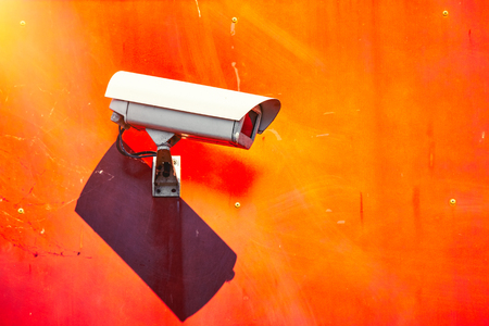 Security CCTV camera installed on a red wall in the city