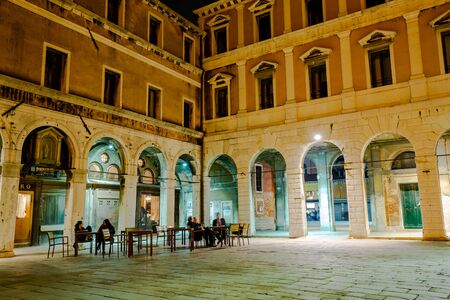 Venice, Italy - March 20, 2015:Tourists sitting at tables and relaxing outside old building on ancient square at night in Veniceのeditorial素材