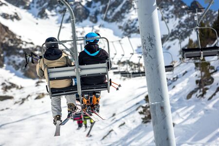 La Mongie, France - March 21, 2019:Back view of anonymous skiers riding chairlift over snowy mountain slope while resting on resort on sunny winter dayのeditorial素材