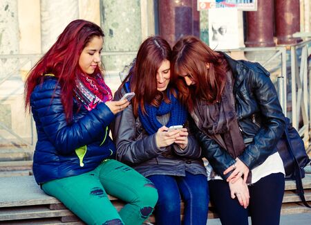 Venice, Italy - March 20, 2015:Group of teenagers in casual outfits browsing smartphones while sitting on bench on Piazza San Marco in Veniceのeditorial素材