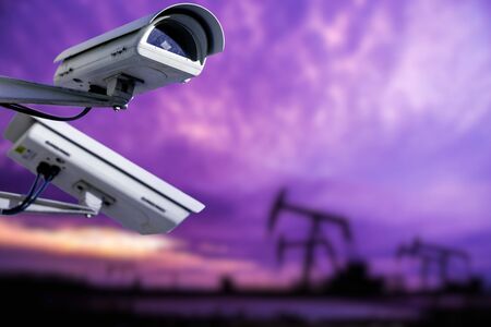 CCTV camera concept with silhouettes of oil well on oil field with nice sunset sky backgroundの写真素材