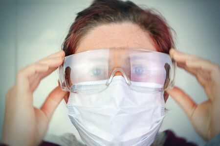 Blurry portrait of Person with medical mask and protective glasses for protection against flu and diseases. Prevention spread of virus and epidemic coronavirus COVID-19の写真素材