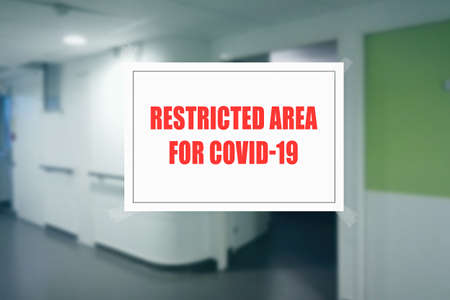 Sign on the door of a hospital corridor indicating an access area reserved for patients with covid-19 or coronavirusの写真素材