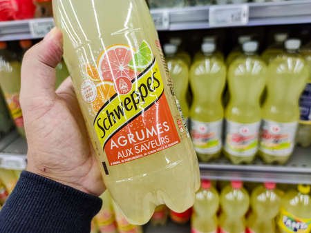 Puilboreau, France - October 14, 2020: Closeup of Man hand buying schweppe citrus soft drink on supermarket with other bottles on backgroundのeditorial素材