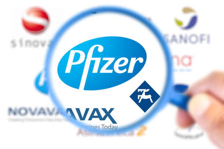 Benon, France - November 20, 2020: Pfizer logotype enlarged with a magnifying glass with other logotype laboratories on blurry backgroundのeditorial素材