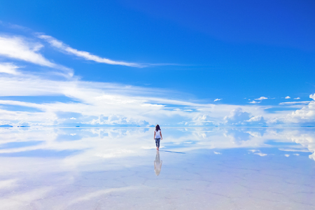 Female walks into the horizon at Salar de Uyuni, the Salt Flats in Boliviaの写真素材