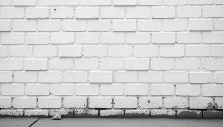 Monochromatic white brick wall background with a concrete baseの写真素材