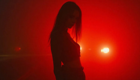 Woman in red light poses in front of headlights