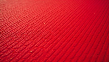 Vibrant red textured surface with parallel ridges background imageの写真素材