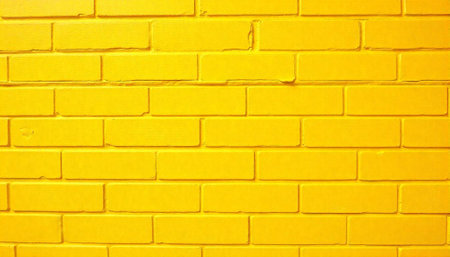 Vibrant yellow painted brick wall texture full frame backdropの写真素材