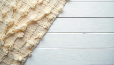 Cream blanket with decorative flowers on white wooden surface