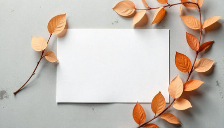 Autumn leaves framing blank white card on gray background