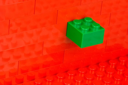 Wall out of red building blocks with a green maverickの写真素材