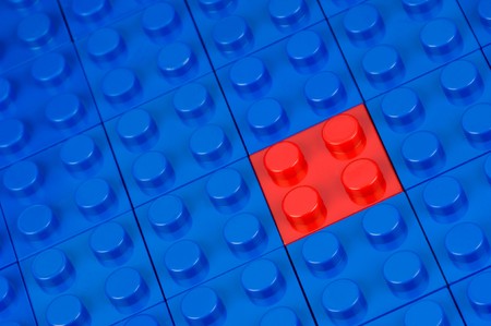 Red building block in a field of blue oneの写真素材
