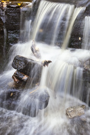 Waterfall with autumn leaves in the water, long exposure time