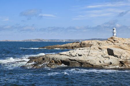 Waves breaking at the rocky coast with a lighthouseの写真素材
