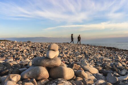 Couple on the beach with a cairn in the foregroundの写真素材