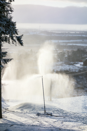 Backlight hrough the snow spray from a snow cannon
