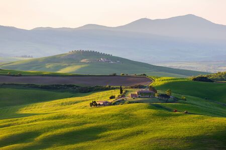 Sunlit field with a farm in Tuscany, Italyの写真素材