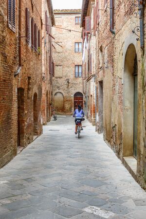 Woman bicycles in an old alleyの写真素材