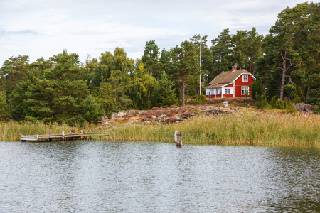 Red cottage by the beach with a jettyの写真素材