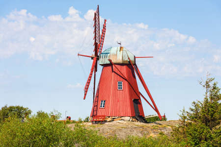 Red wooden windmill on the rocksの写真素材