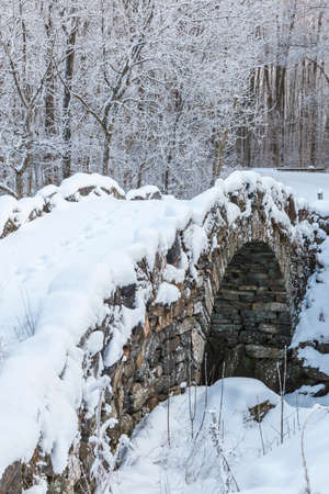 Old arch bridge with snow in a winter landscapeの写真素材