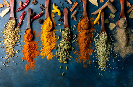 indian spices in wooden spoon on dark backgroundの写真素材