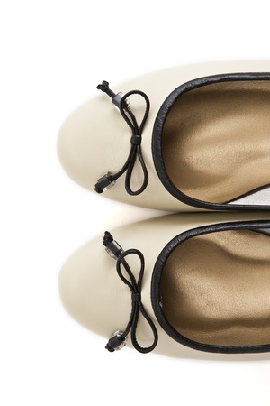 Pair of beige female shoes with black bow over white background の写真素材