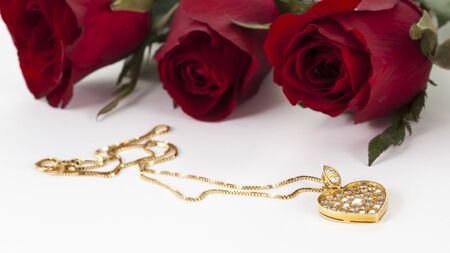 Heart pendant with diamond and red rose on white backgroundの写真素材