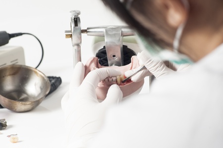 Dental technician working with articulator in dental laboratory 