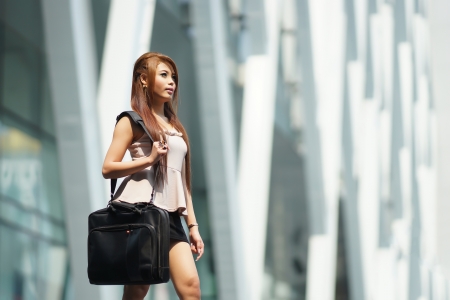 Beautiful business woman walking outside her office with briefcase.の写真素材