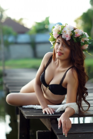 Young sexy Asian woman in black lingerie sitting on the wooden bridge outdoor.の写真素材