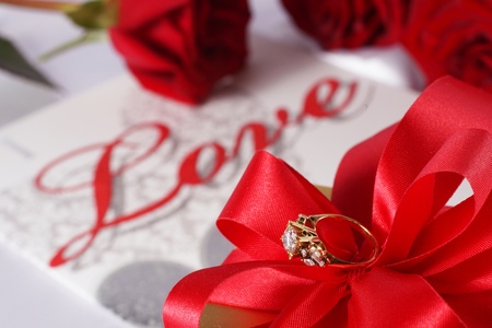 Golden diamond ring with gift box and red rose on with satin backgroundの写真素材