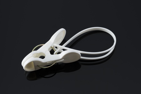 One white plastic clothespins on black background