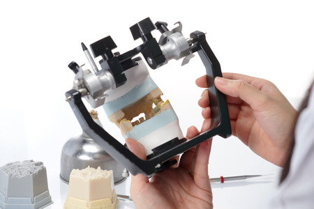Dental technician working with articulator in dental laboratory
