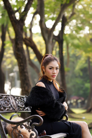 Beautiful Asian lady in black dress, posing in the park, greenery in the background, model is Thai Ethnicity.の写真素材