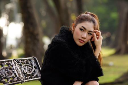 Beautiful Asian lady in black dress, posing in the park, greenery in the background, model is Thai Ethnicity. の写真素材