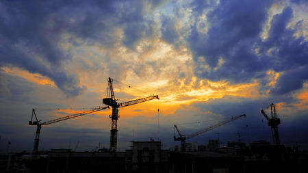 Industrial landscape with silhouettes of cranes on the sunset background.の写真素材