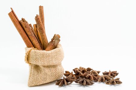 Cinnamon sticks in sack bag with star anise, isolated on white background.の写真素材