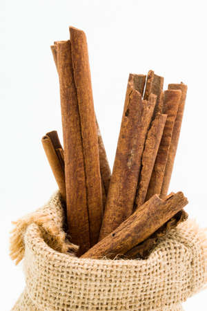 Cinnamon sticks in sack bag, isolated on white background.の写真素材