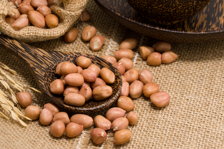 No shell dry peanut in wooden spoon and sack. Focus at nut in spoonの写真素材